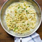 Fettuccine Alfredo in a stainless steel skillet.