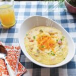 Cheesy Grits in a white oval bowl on a blue checkered table cloth