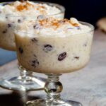 Rice pudding in a dessert dish on a wooden counter.