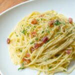 Spaghetti Carbonara on a white plate on a wooden table.