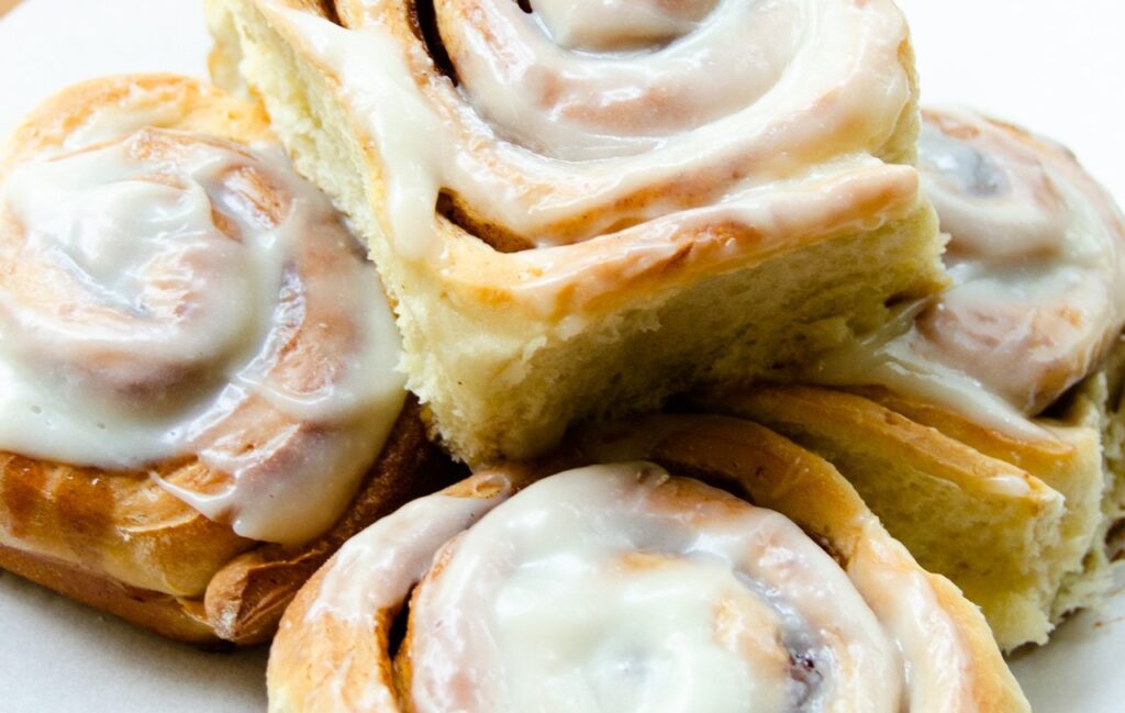 Cinnamon Rolls stacked on a piece of white parchment paper.