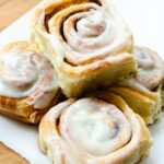 Cinnamon Rolls stacked on a piece of white parchment paper.