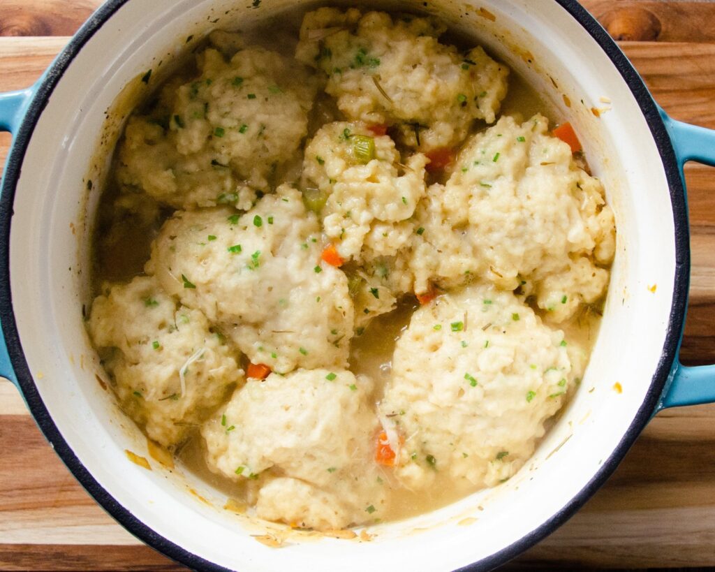 A cast iron pot with chicken and dumplings in it.