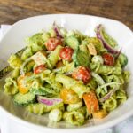 Creamy Pesto Pasta Salad in a white bowl on a wooden table.