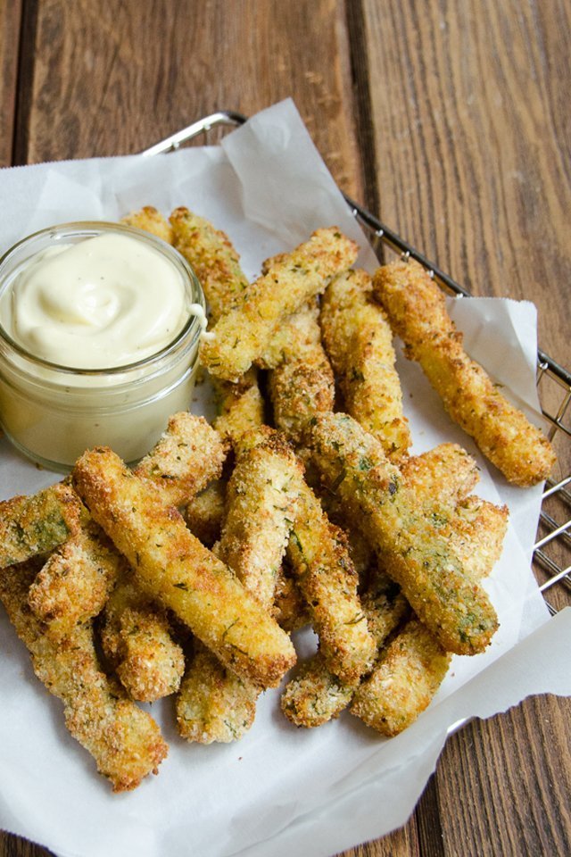 Air-fried zucchini fries in a metal basket lined with white parchment paper.
