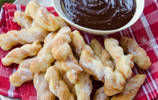 Air fried sugared dough dippers on a plate with chocolate sauce.