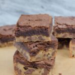 Brownie and Blondie Layer Bars stacked on parchment paper.