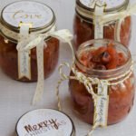 Pear Cranberry Chutney in jars with gold and white ribbons.