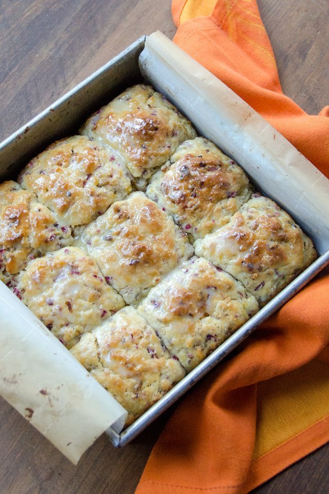 A parchment lined square baking pan with cranberry orange pecan buttermilk biscuits inside.
