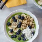 Green smoothie bowl on a marble countertop.