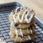 A stack of three iced oatmeal cookies on a cooling rack.