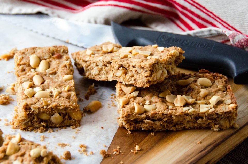 Peanut butter breakfast bars on a wooden cutting board with knife.