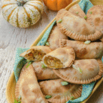 pumpkin and pork empanadas on a yellow platter on a white wooden table