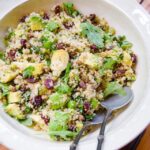 Quinoa salad with artichokes and dried cherries in a white bowl on a wooden table.