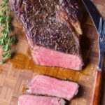 sous vide rib eye steak on a wooden cutting board.