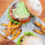 Black Bean Turkey Burgers on a gray marble with sweet potato fries scattered around.