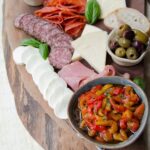 Tuscan antipasti board with meats, cheeses, roasted peppers, olives and marinated mushrooms.