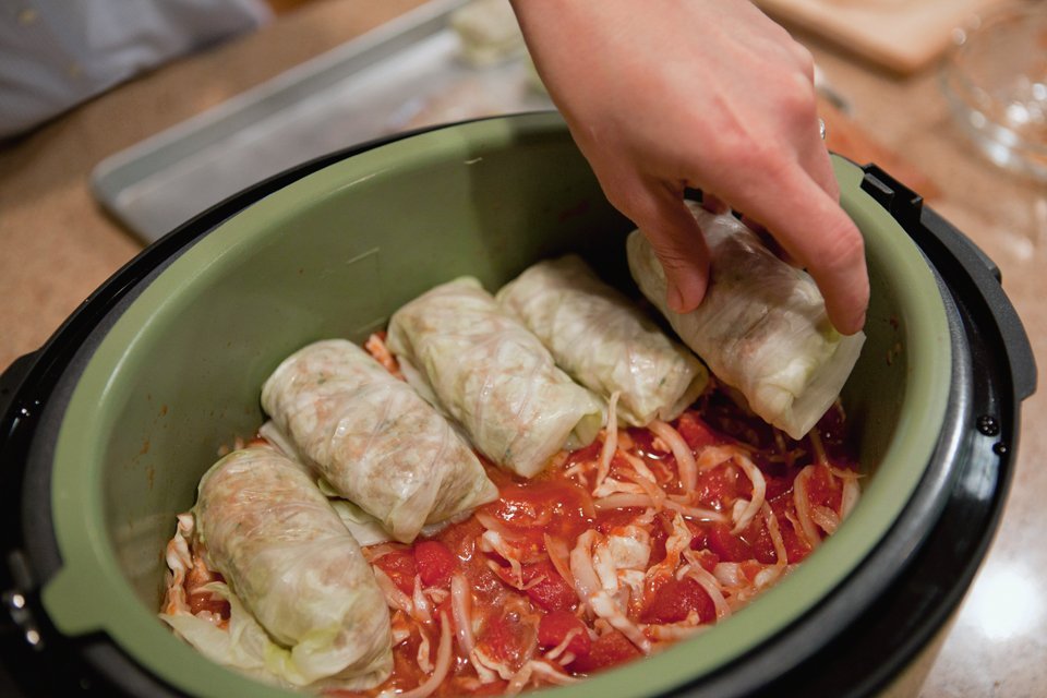 Placing cabbage rolls in the tomato sauce in the pressure cooker.