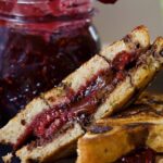 Close up of a chocolate berry sandwich with a jar of jam in the background.