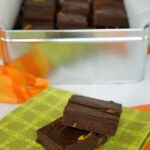 A tin of dark chocolate orange fudge with a couple of pieces out front on a napkin.