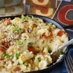 Bacon Tomato Mac and cheese in a dish with a spoon scooping out a portion.