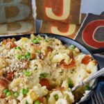 Bacon Tomato Mac and cheese in a dish with a spoon scooping out a portion.