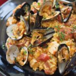 Instant Paella in a dark dish with serving utensils.