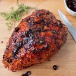 Air Fried Turkey Breast with Cherry Glaze on a wooden cutting board with a knife along side.