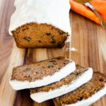 Carrot Cake Loaf with Cream Cheese Icing on a cutting board with three slices cut.