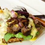 Open Faced Steak Sandwich with Béarnaise Sauce on a white plate.