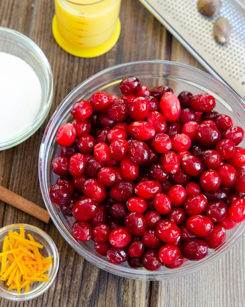 Ingredients for Thanksgiving Cranberry Sauce on a wooden table.