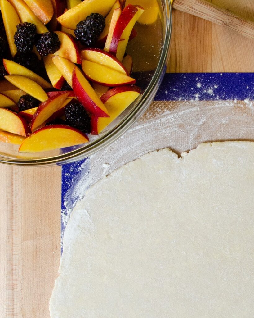 Easy Fruit tart before being assembled - fruit in a bowl and a rolled out circle of pastry.