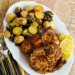 Honey Mustard Pork Chops on a platter with roasted Brussels sprouts and potatoes.