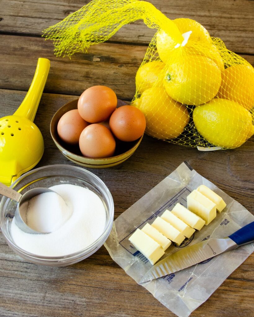 Ingredients for lemon curd on a wooden table - lemons, butter, sugar, eggs.