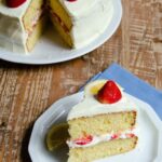 Strawberry Lemon Mascarpone Shortcake piece on a plate with the whole cake behind.