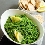 Edamame-Kale dip in a white bowl with crackers in a second bowl behind.
