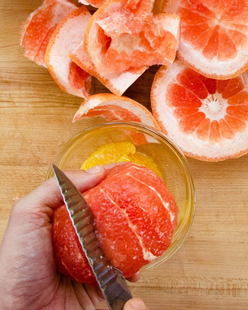 Paring knife slicing into grapefruit to remove supremes.