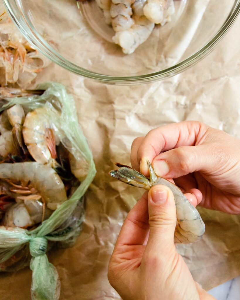 Hands showing the pointed fin in the tail section of shrimp - the last step in how to peel and devein shrimp.