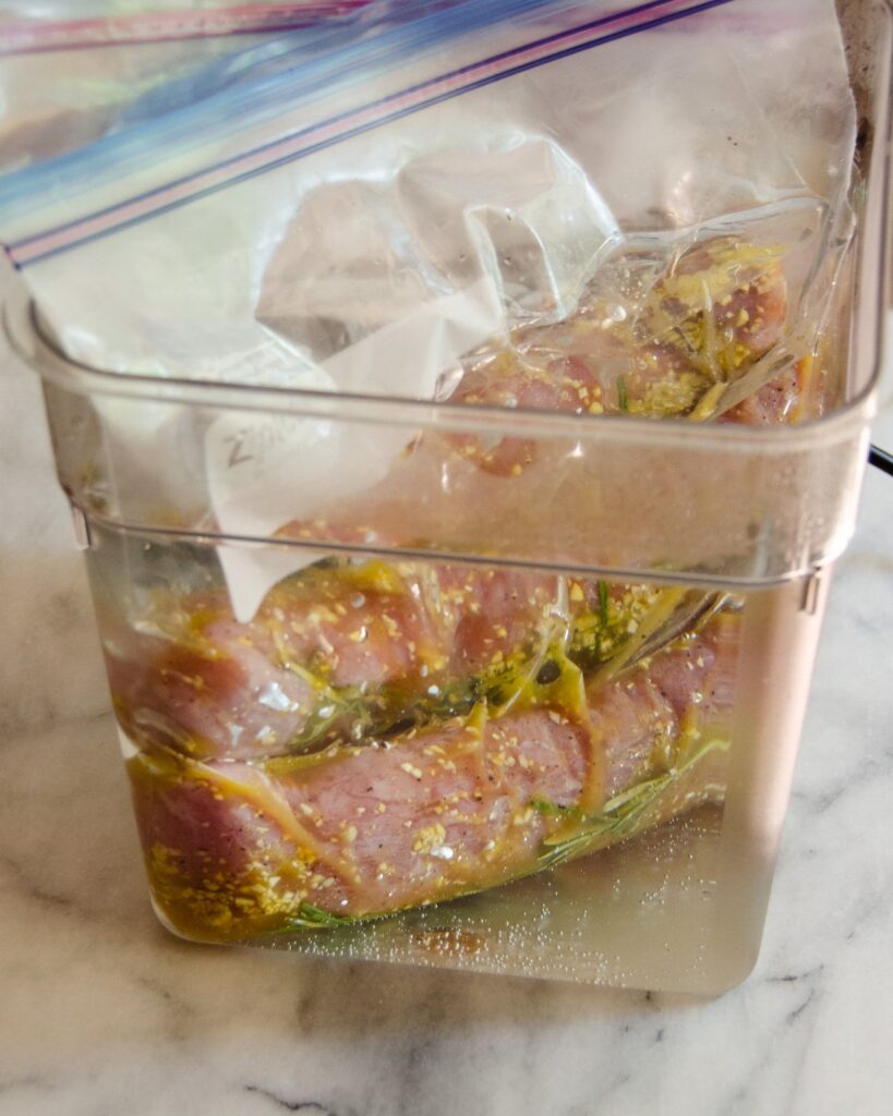 Two pork tenderloins cooking in a sous vide water bath.