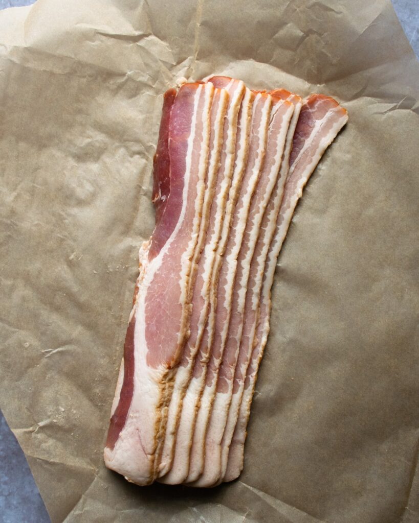 Raw bacon on brown paper.