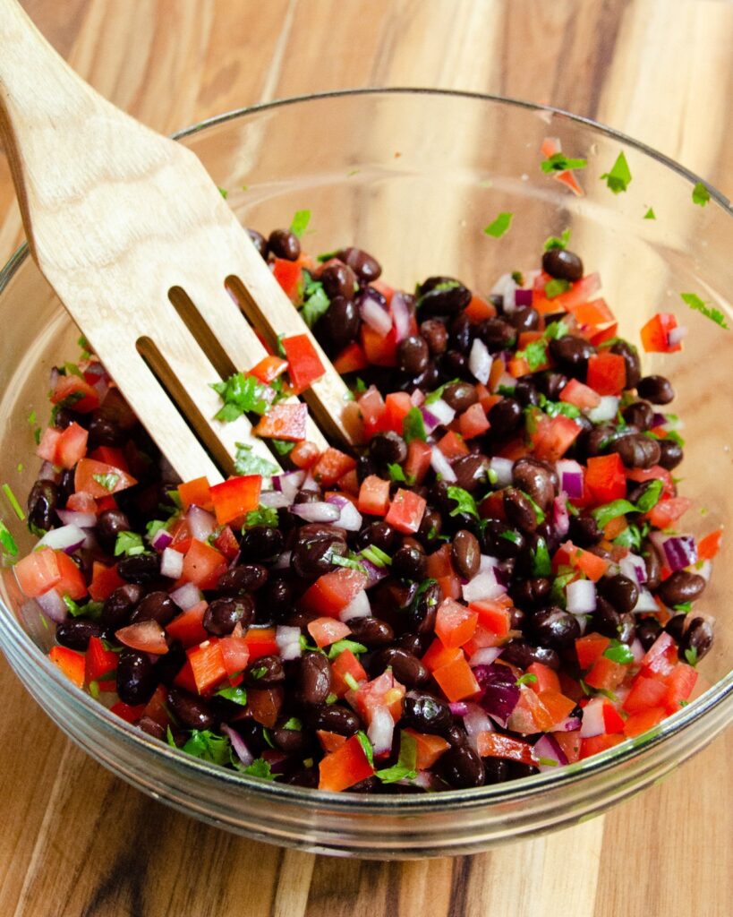 Black bean salsa in a bowl with a wooden spoon.
