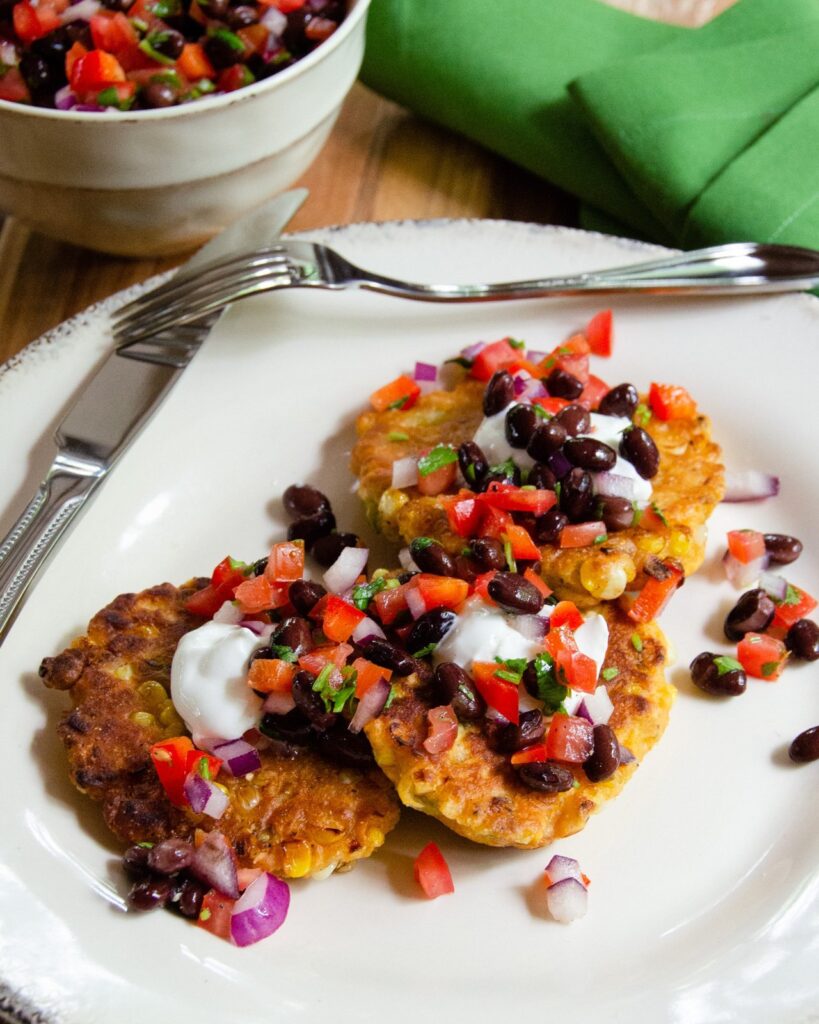 Spicy Corn Cakes with black bean salsa on a white plate with green napkin.
