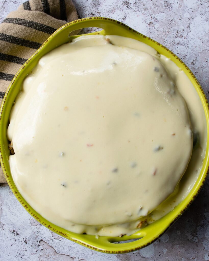 Cheese sauce covering a casserole on a cement countertop.