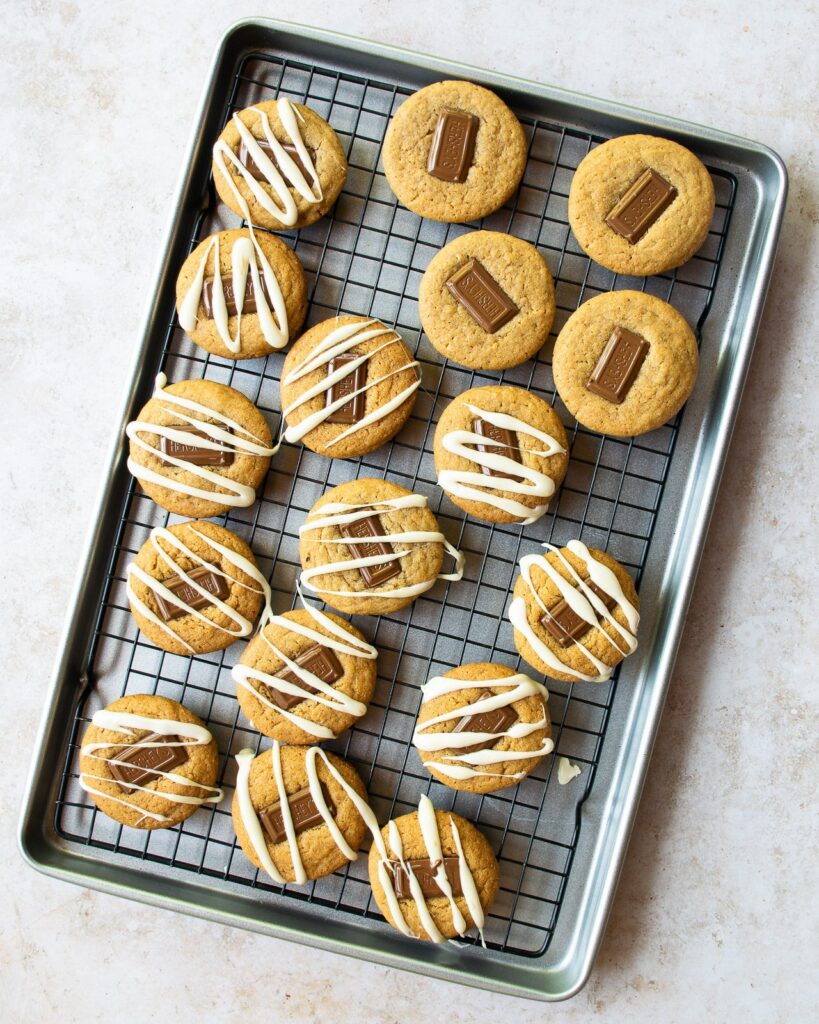 S'mores cookies on a baking sheet, some drizzled with marshmallow and some plain.