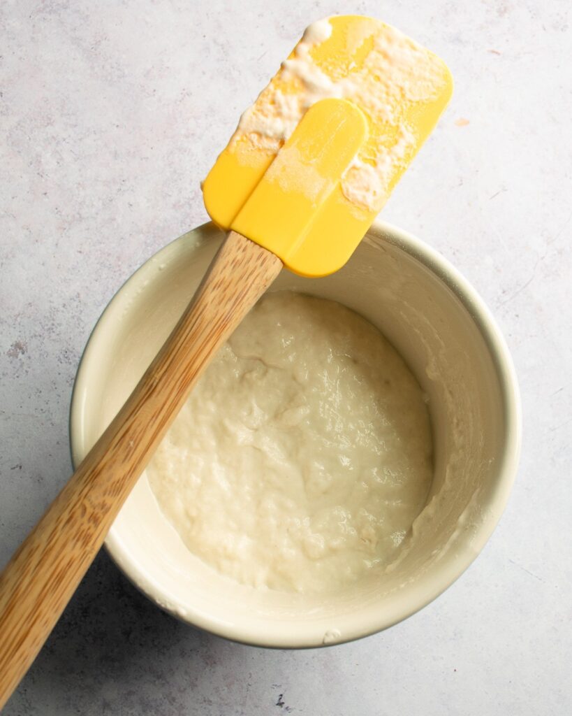 Poolish in a bowl with a yellow spatula.