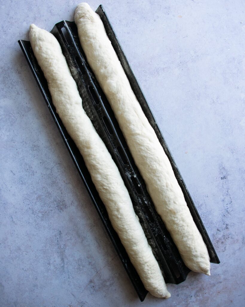 Two raw baguettes in a baguette Pan.