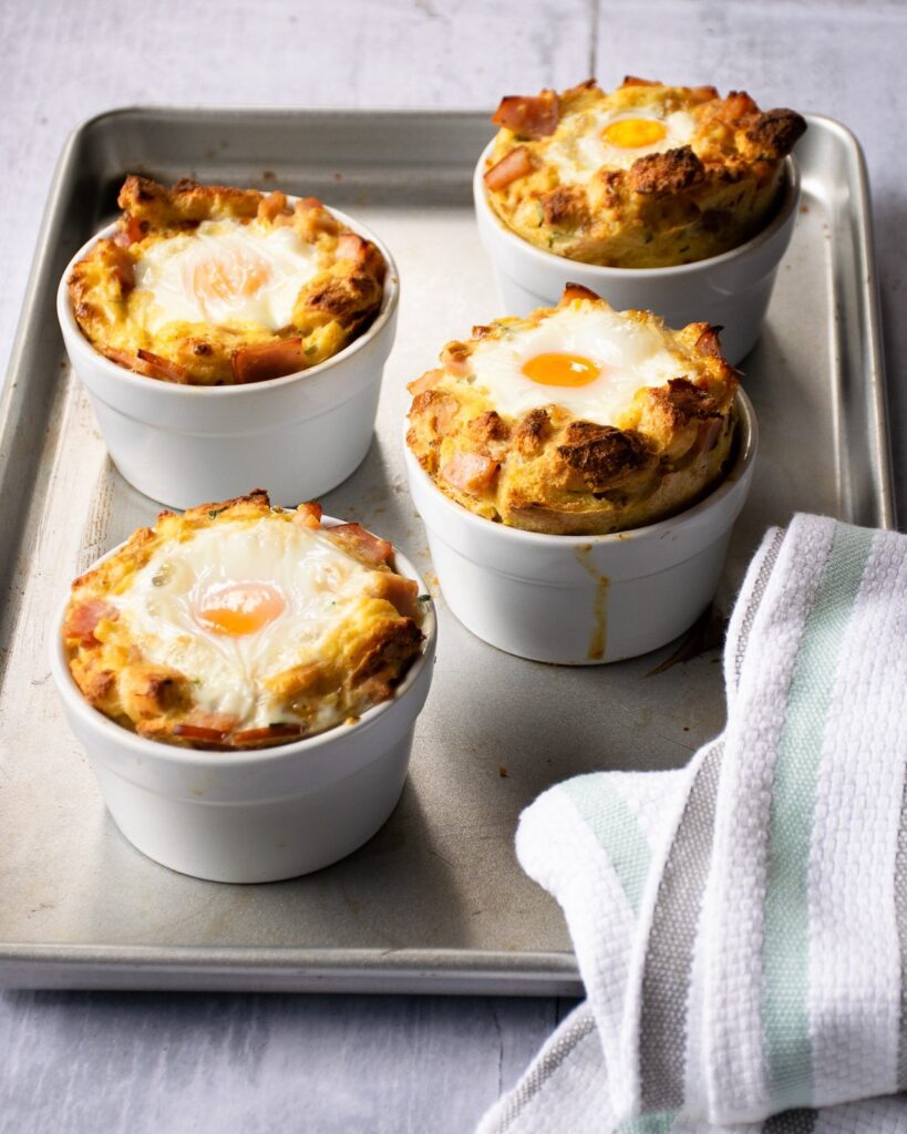 Individual eggs benedict bread puddings on a sheet pan coming out of the oven.