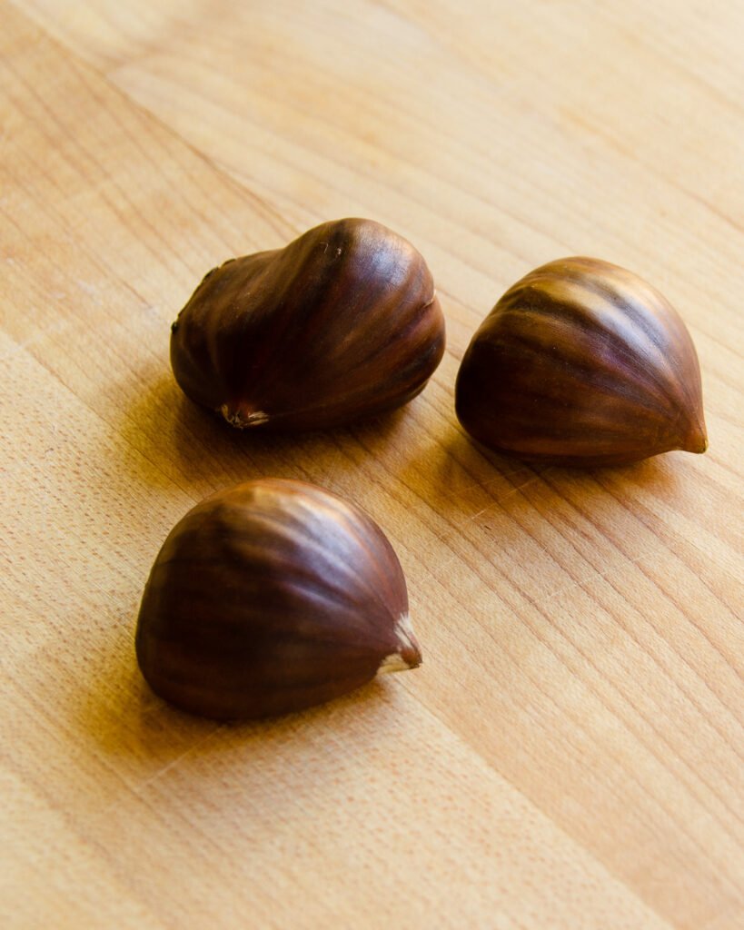 Three chestnuts on a cutting board.
