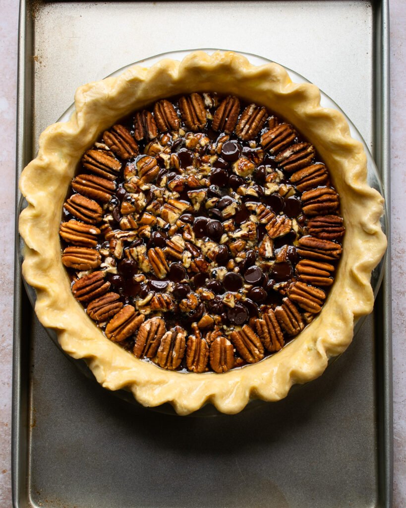 Raw chocolate bourbon pecan pie on a baking sheet ready for the oven.