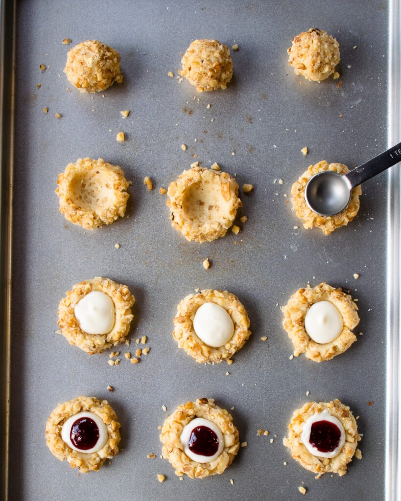 A teaspoon making a divot in a raw cookie on a baking sheet.